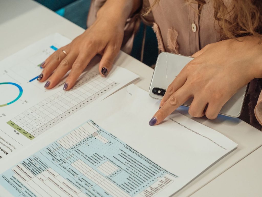 Empreendedora analisa documentos financeiros com gráficos sobre uma mesa.