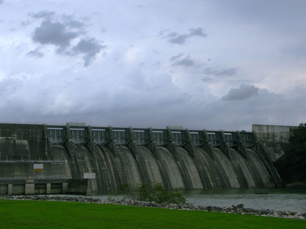 Barragem de concreto de uma usina hidrelétrica sob um céu carregado.