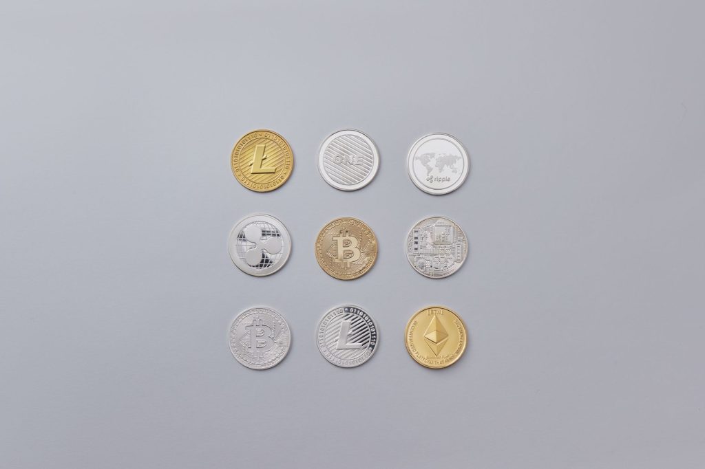 Diferentes moedas de criptomoedas dispostas sobre um fundo cinza neutro
